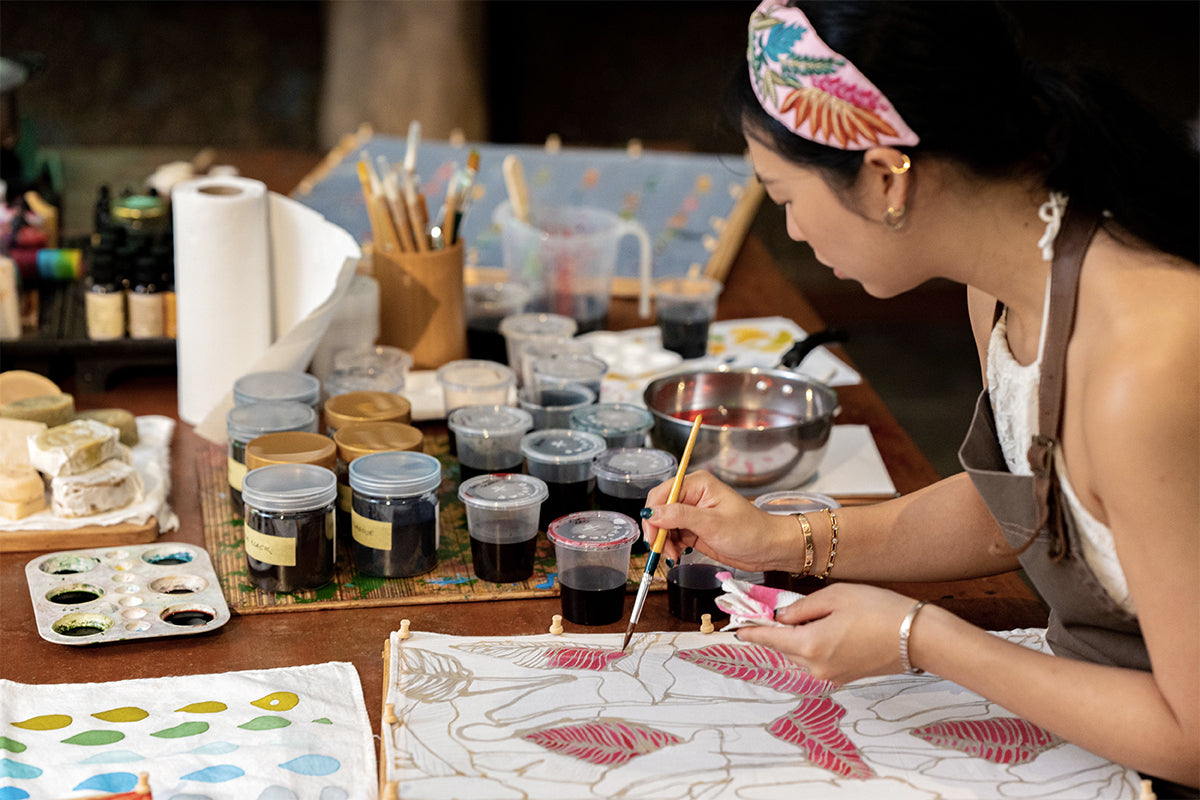 Aishah chose her colours and carefully paints on the waxed fabric