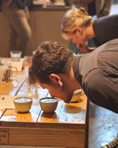 A person assessing the aroma of a coffee in a cupping bowl.