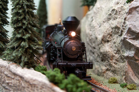 A black locomotive travels through a mountainous HO scale railroad scene