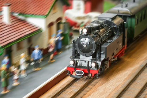 A model HO train in focus against a blurry train scene