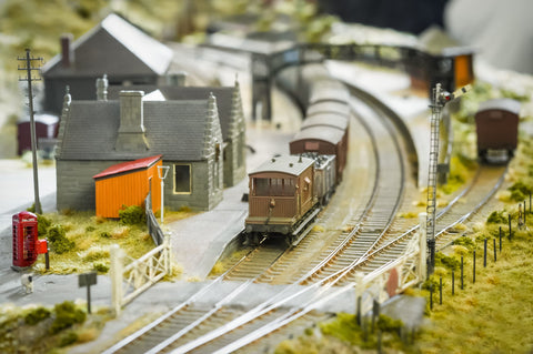 A model train set with homes, fences, electric posts, and a train on a track