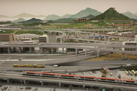 A model set with trains, mountains, highways, cars, and model train buildings