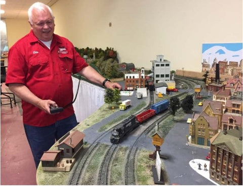  A man running a HO Scale model train through the house.