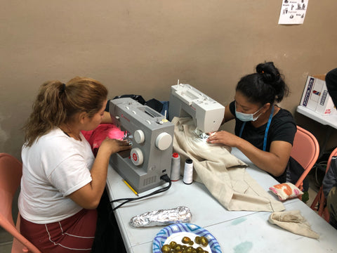 2 women in refugee camp womens sewing cooperative working together