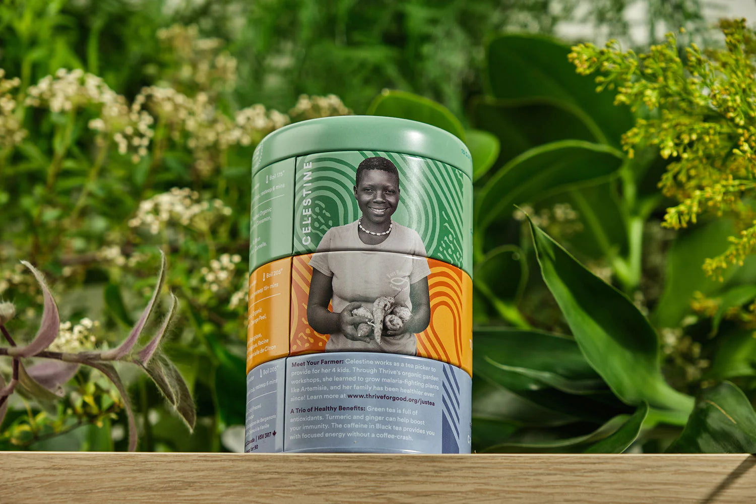 artisan.woman.smiling in front on the back of a tea container with tea leaves behind .kenya.loosleaf.tea.farmer.partnership.do.good.shop