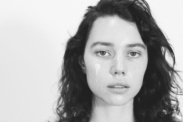 Black and white picture of Young women looking sad with cream under her left eye