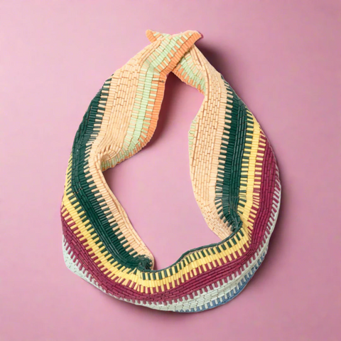 Maleek mini scarf necklace with blue, rose, yellow, green, and orange beads against a pink background