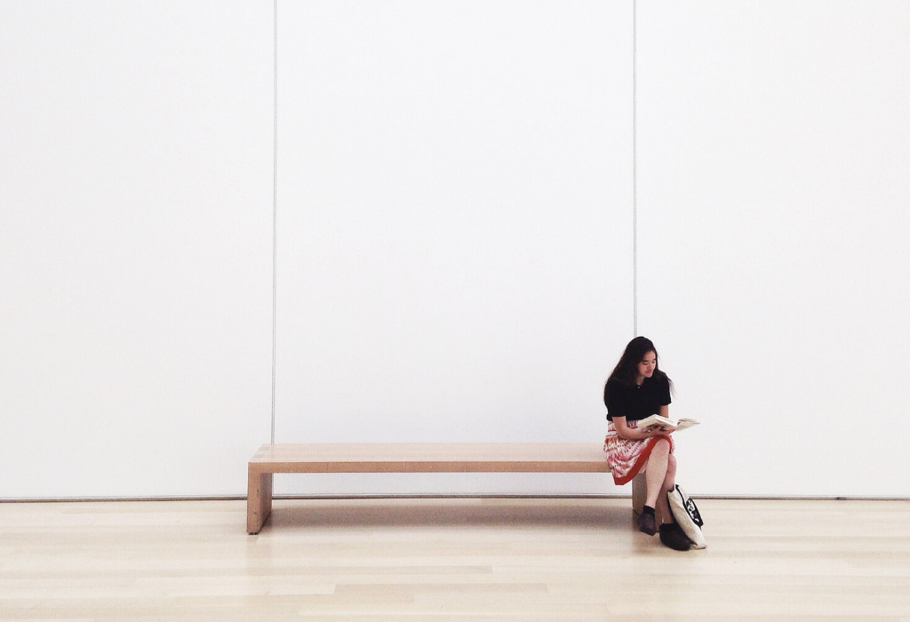 Woman sitting alone at an art gallery reading by herself