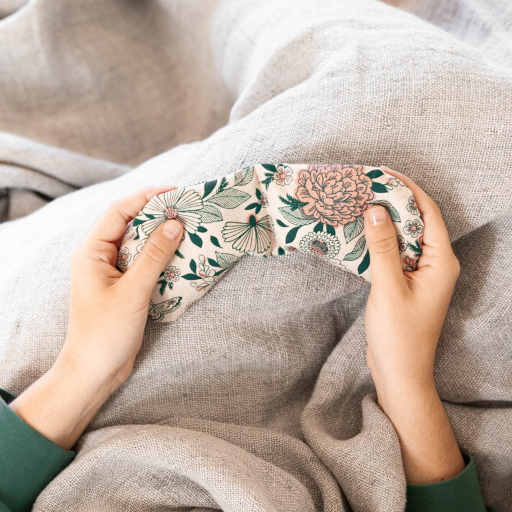 persons hands holding hot cold therapy pack on blanket