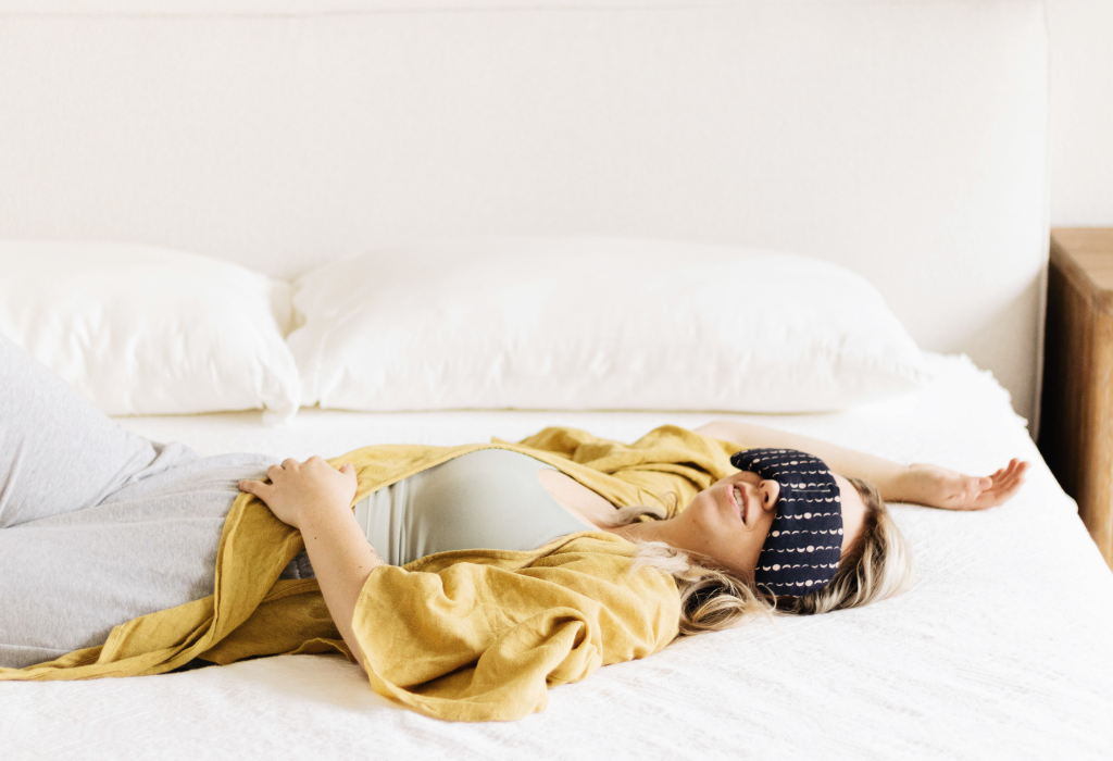 Woman laying down in bed relaxing with slow north solstice migraine mask therapy pack