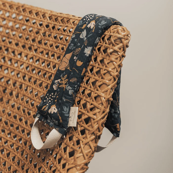 An image of a Slow North heated neck wrap on a wicker chair