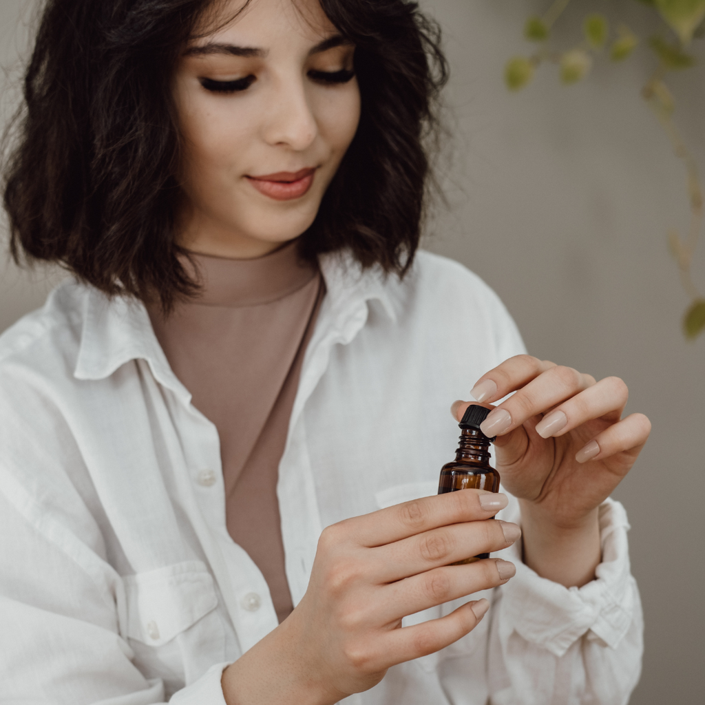 brunette woman holding brown bottle of lavender essential oil