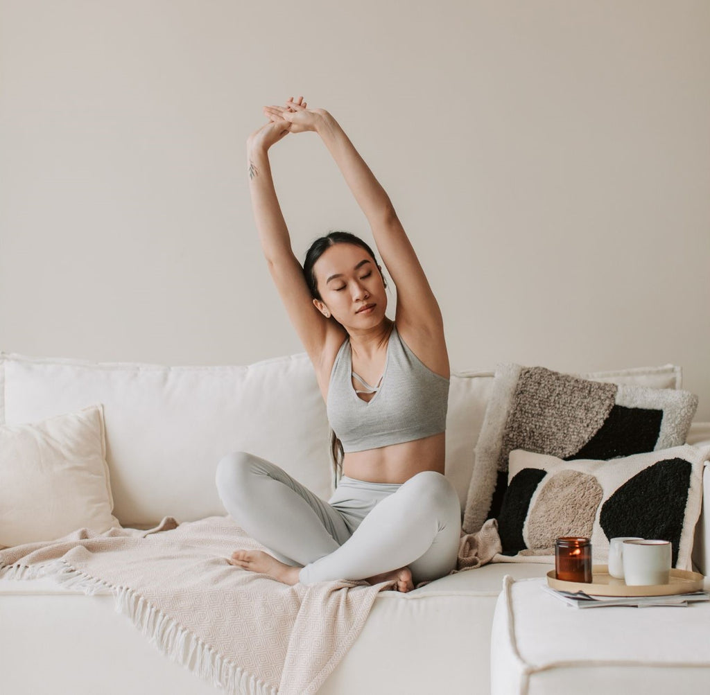 woman sitting on a couch stretching her arms up overhead