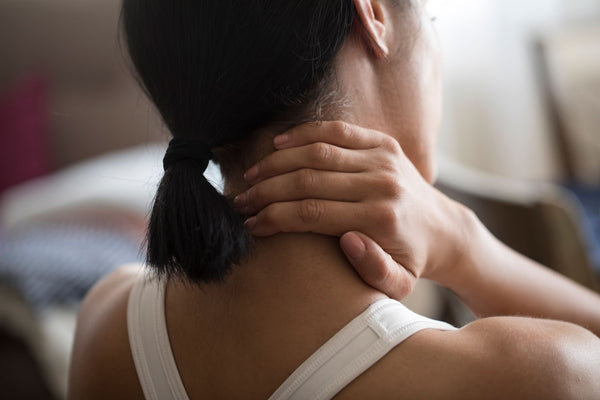 An image of a woman massaging a painful spot on her neck and shoulders