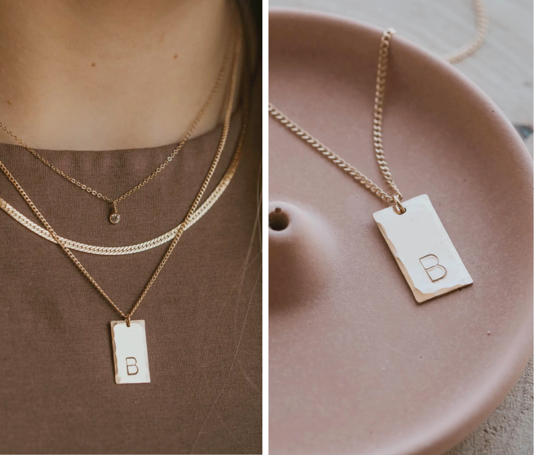 A stamped initial necklace created by Hello Adorn shown as a layered necklace in gold.