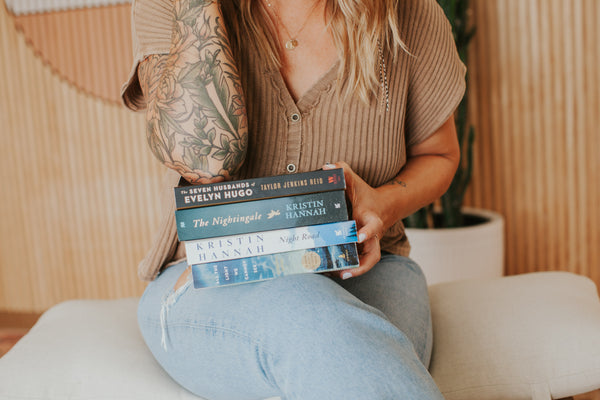 Jess holding stack of books on lap. 