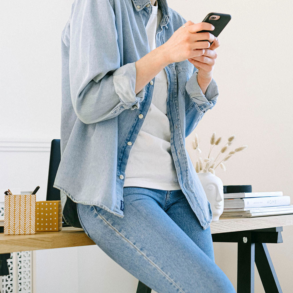 Leaning against desk checking phone