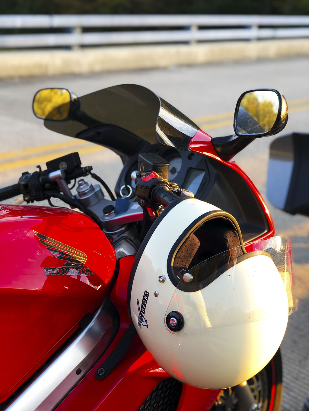 Katy's red Honda and white Biltwell helmet on the handles