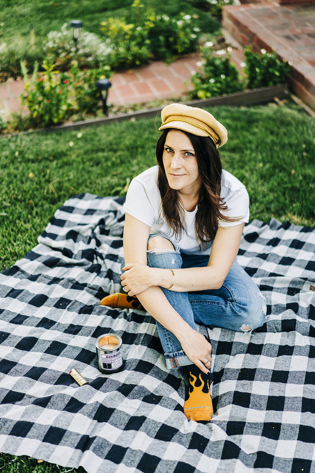 Katy the founder of Shoppe 815 sitting on a picnic wearing flame socks with a tin candle lit.