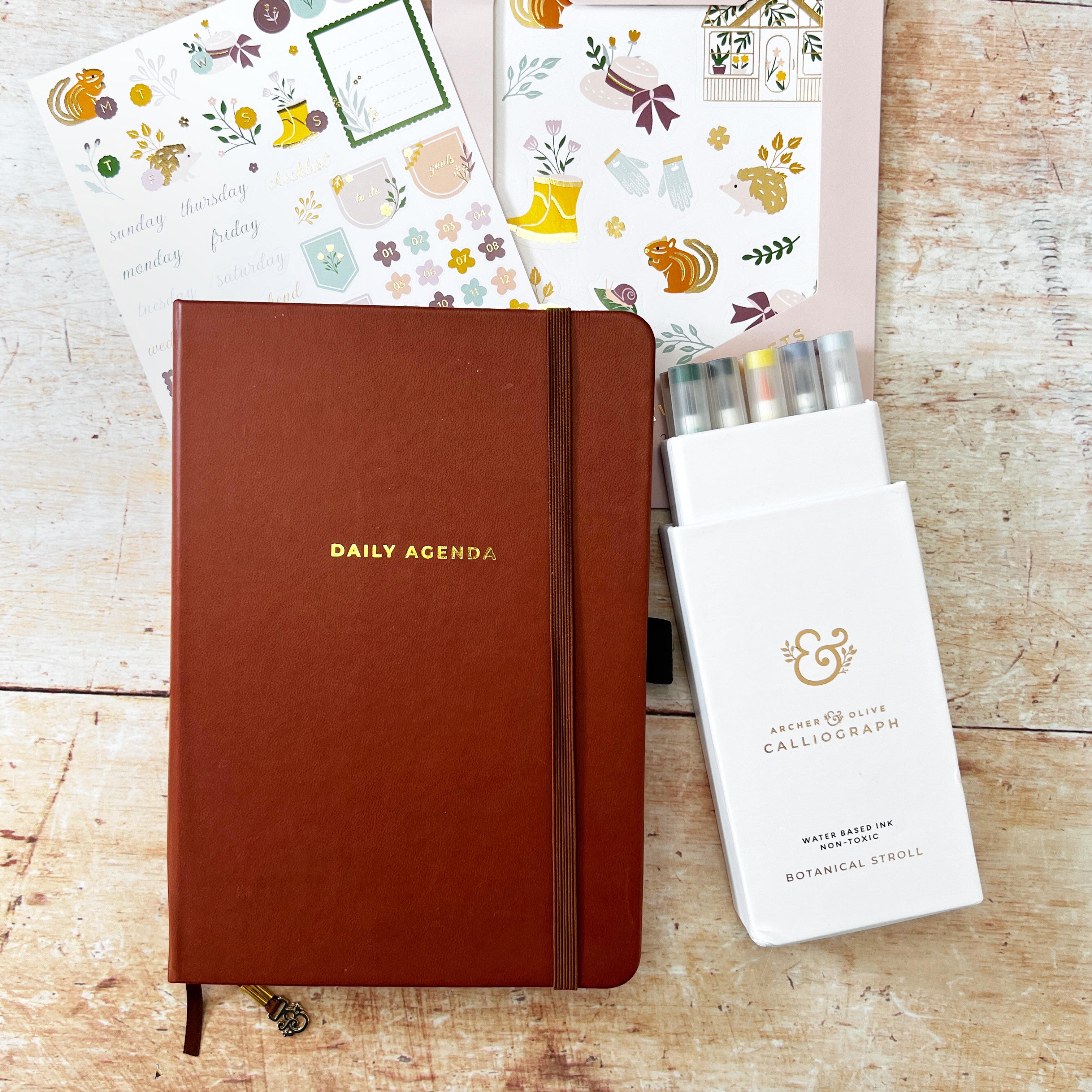 A brown planner with leather cover, pens and spring themed stickers