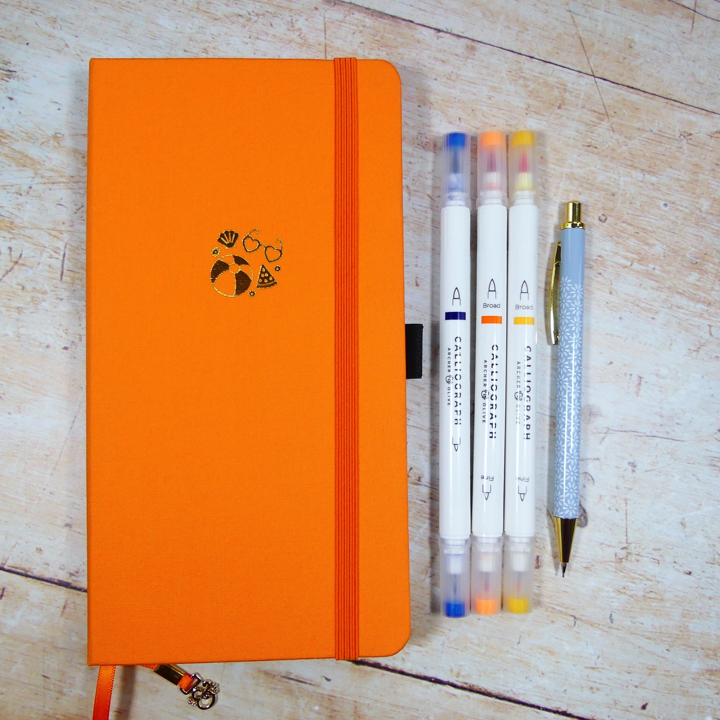 Orange travelers journal, tall and narrow with calliograph brush pens