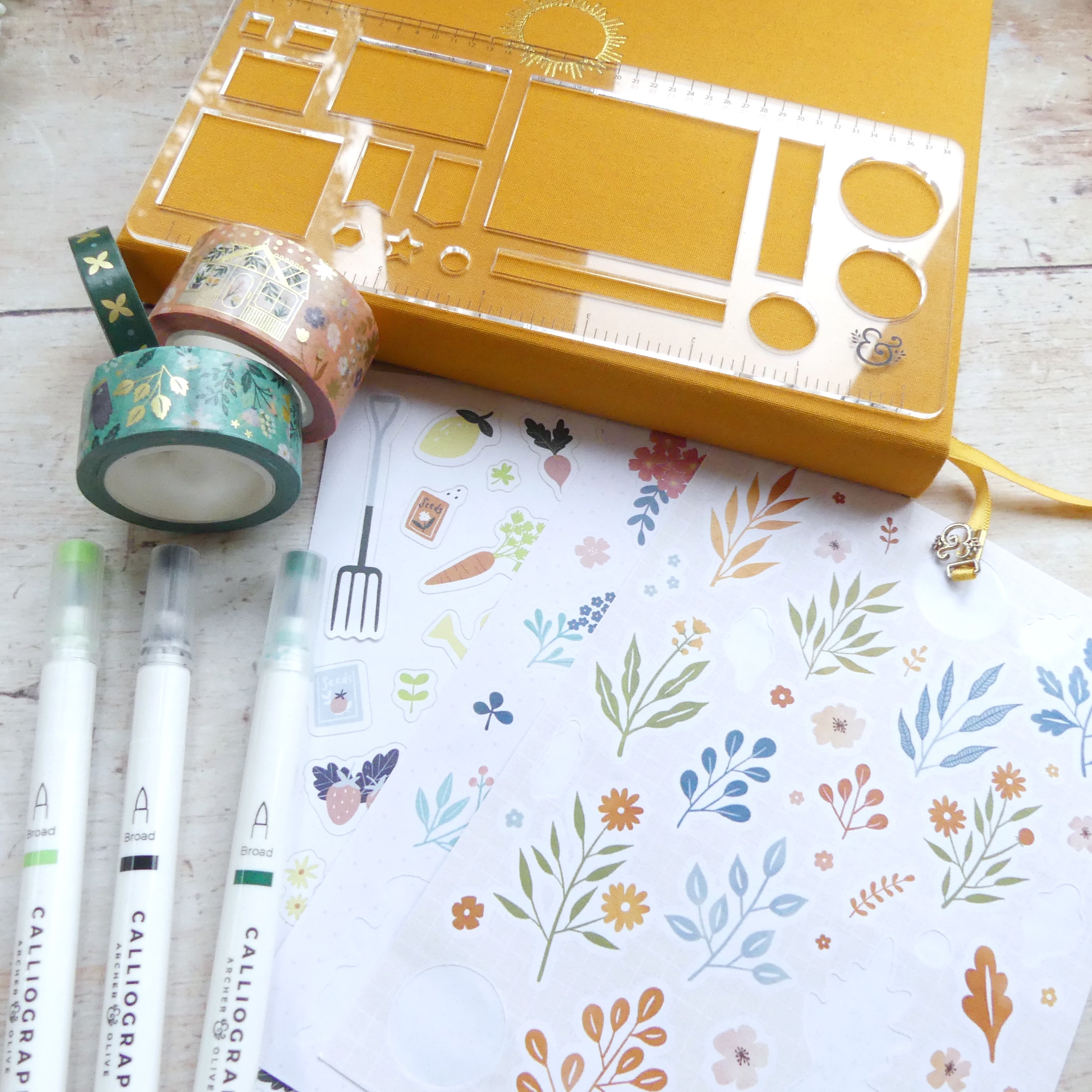 Journal surrounded by stickers, washi and pens