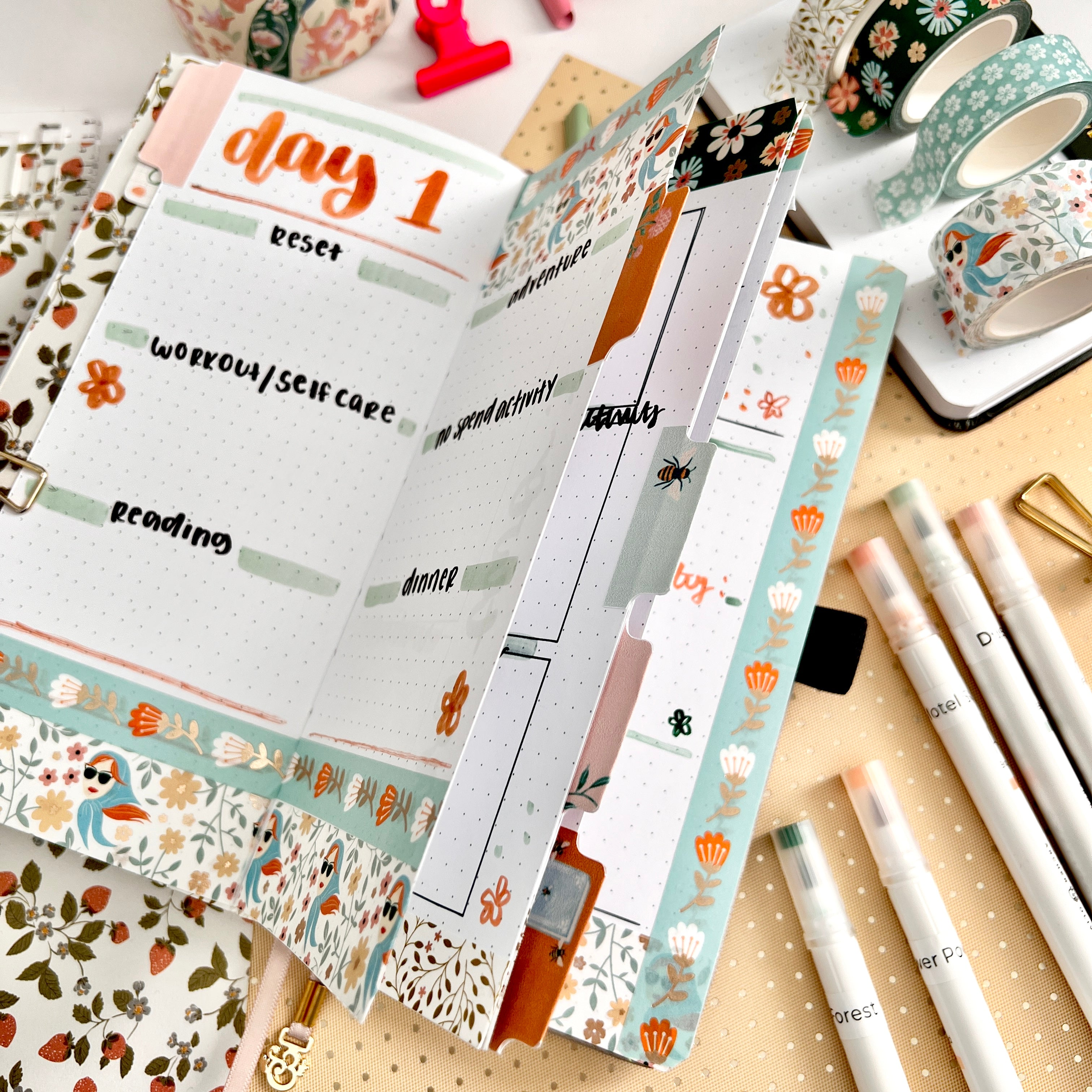 Traveler's size notebook open showcasing the use of planner tabs in a flat lay photo surrounded by stationery