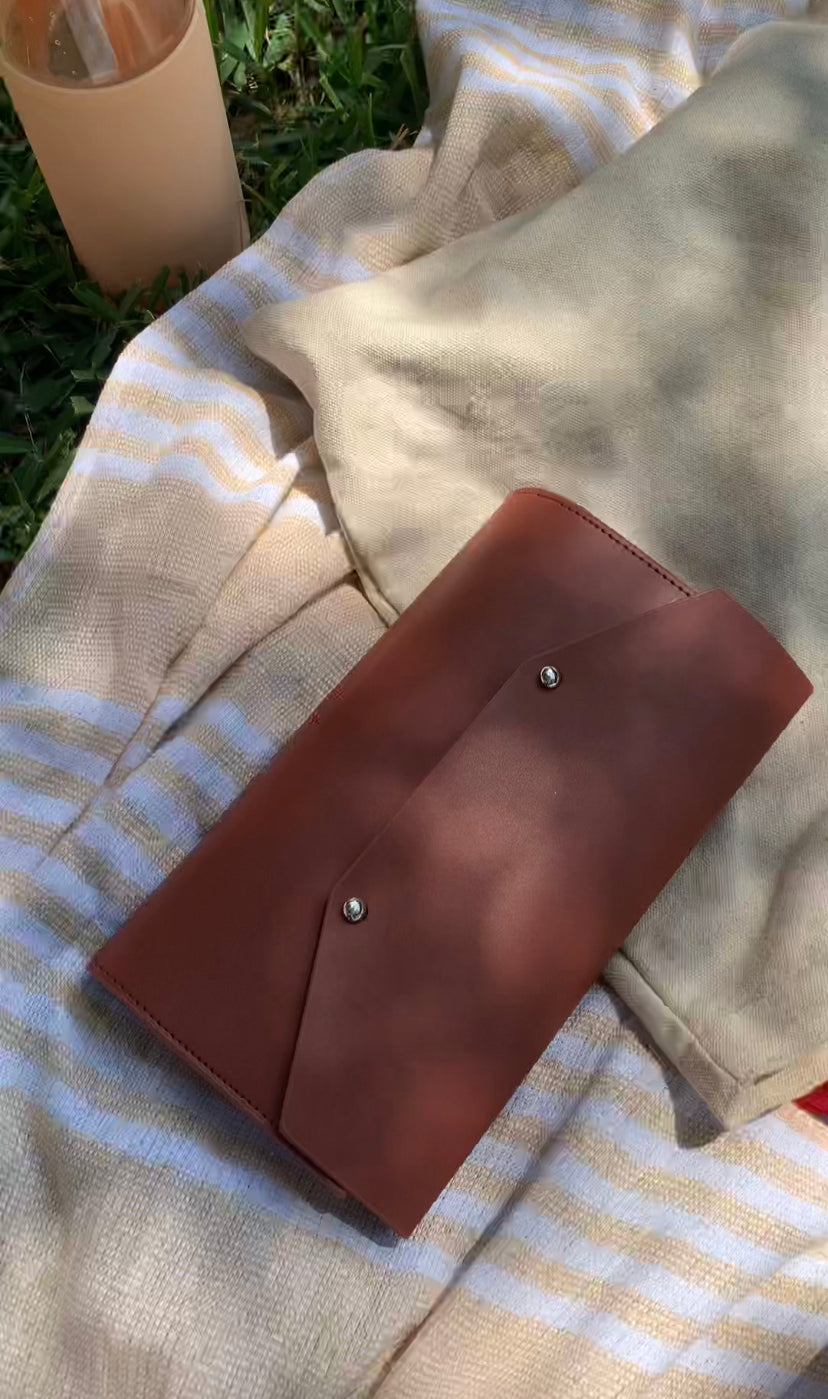 the journal cover on a picnic blanket with a water bottle outside at the park