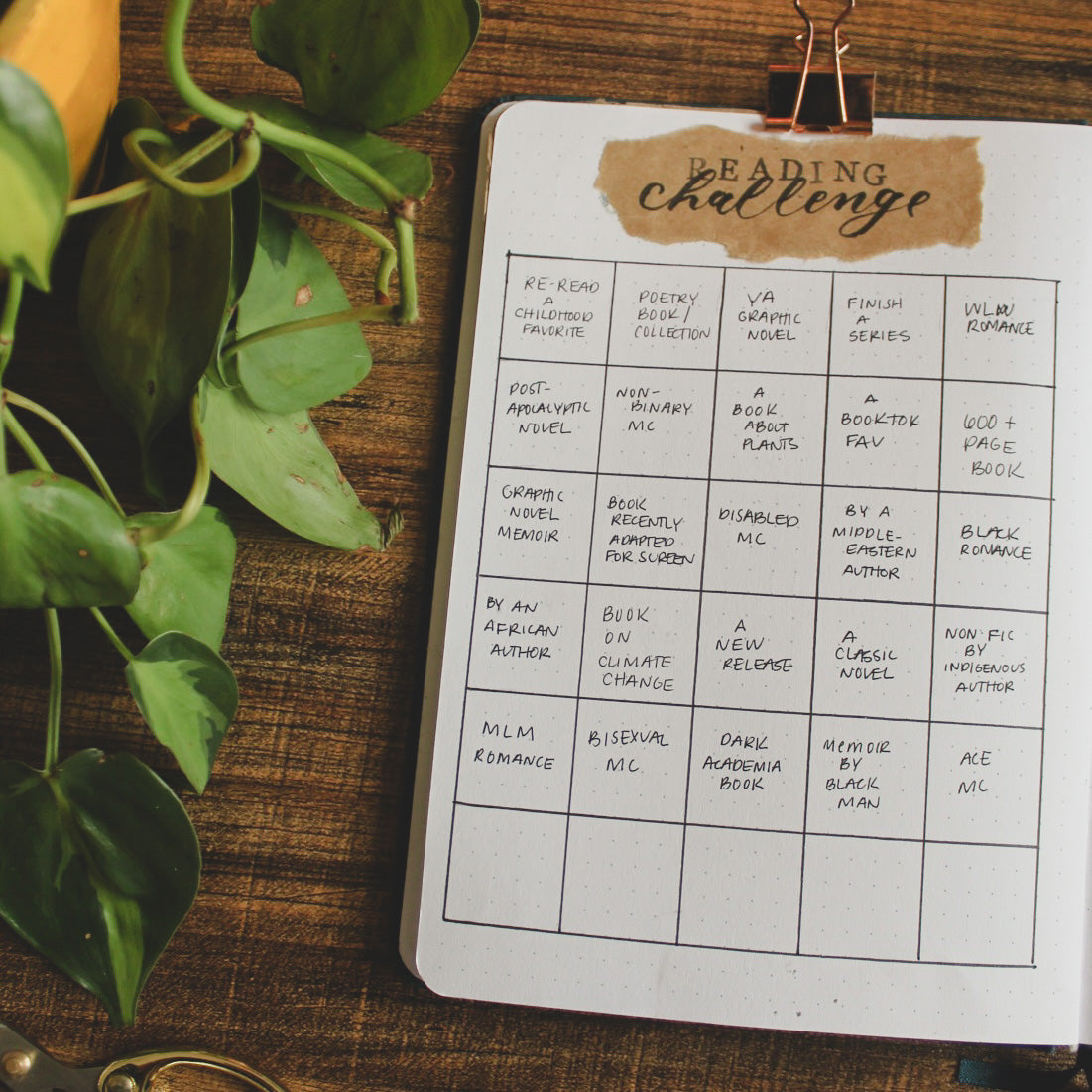 One page of a dot grid notebook is open on a dark surface. The page is titled 'Reading Challenge' and has several squares in it with different reading challenge prompts.