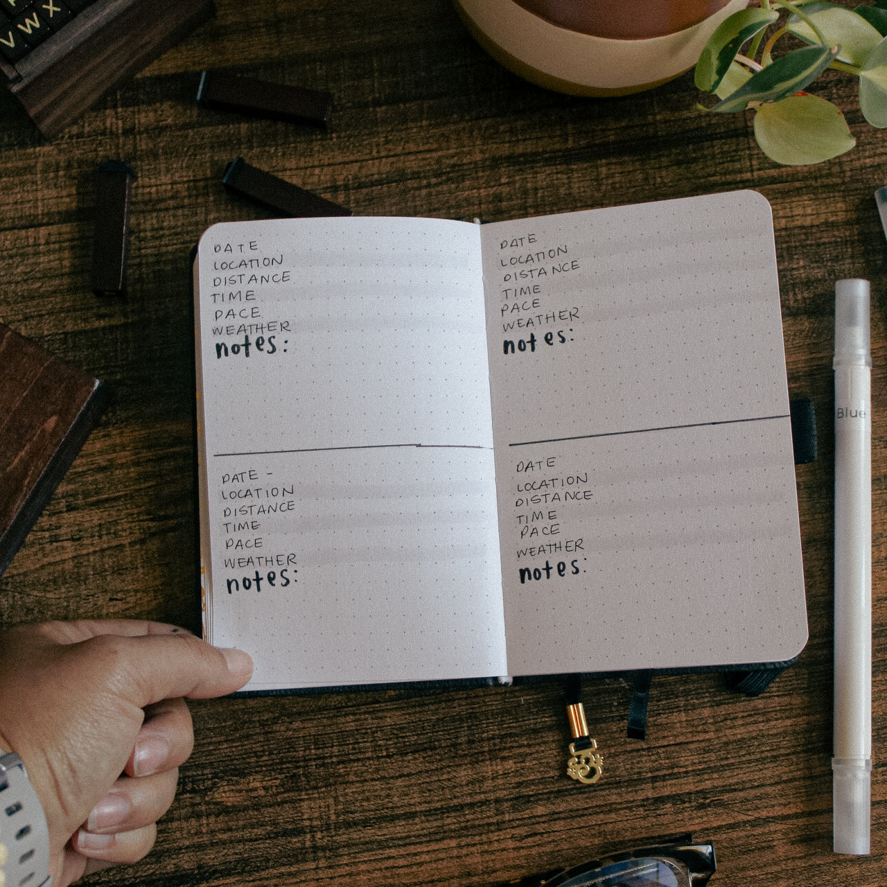 A notebook is lying open on a desk. Each page is divided into two sections. Each section has a place to track date, location, time, pace, weather, and additional notes about the run.