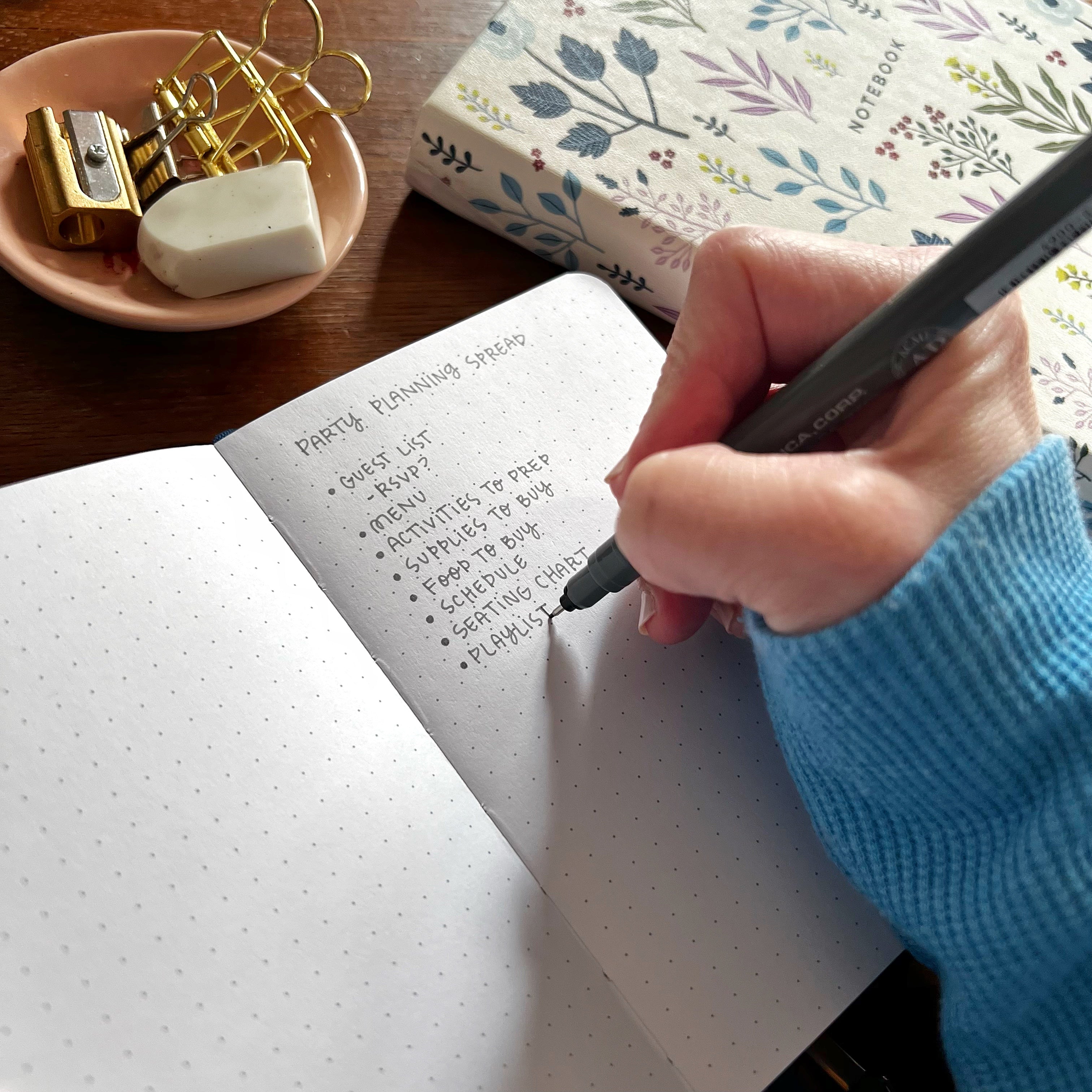 Photo of hand with pen writing a list of ideas in a notebook