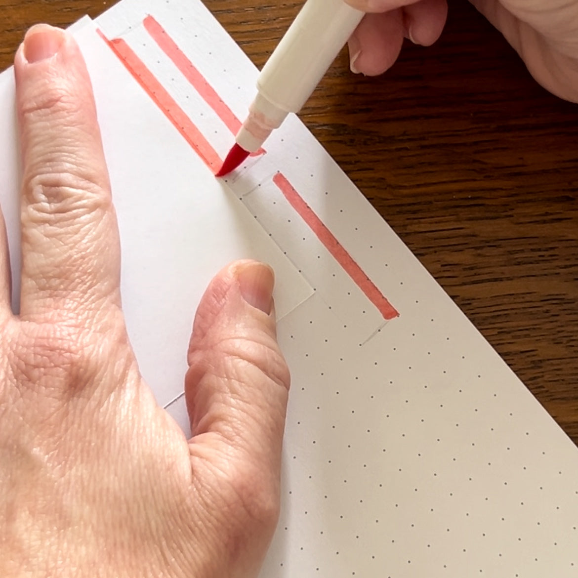 Photo of using scrap paper as a ruler for Calliograph pen to get a straight edge