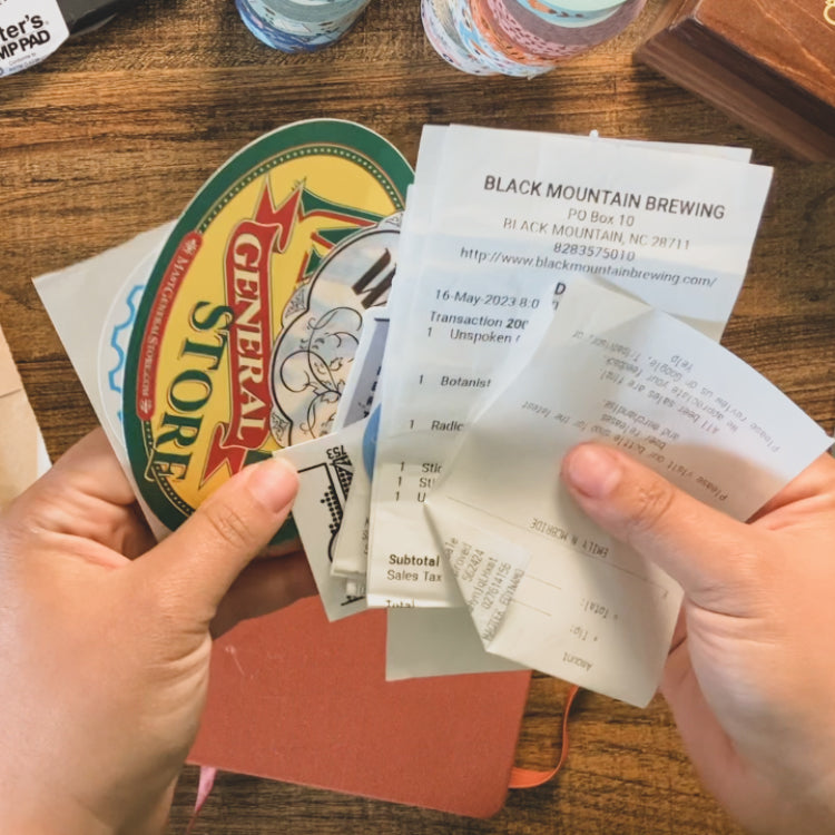 Emily is holding up some receipts and stickers she collected from her trip.