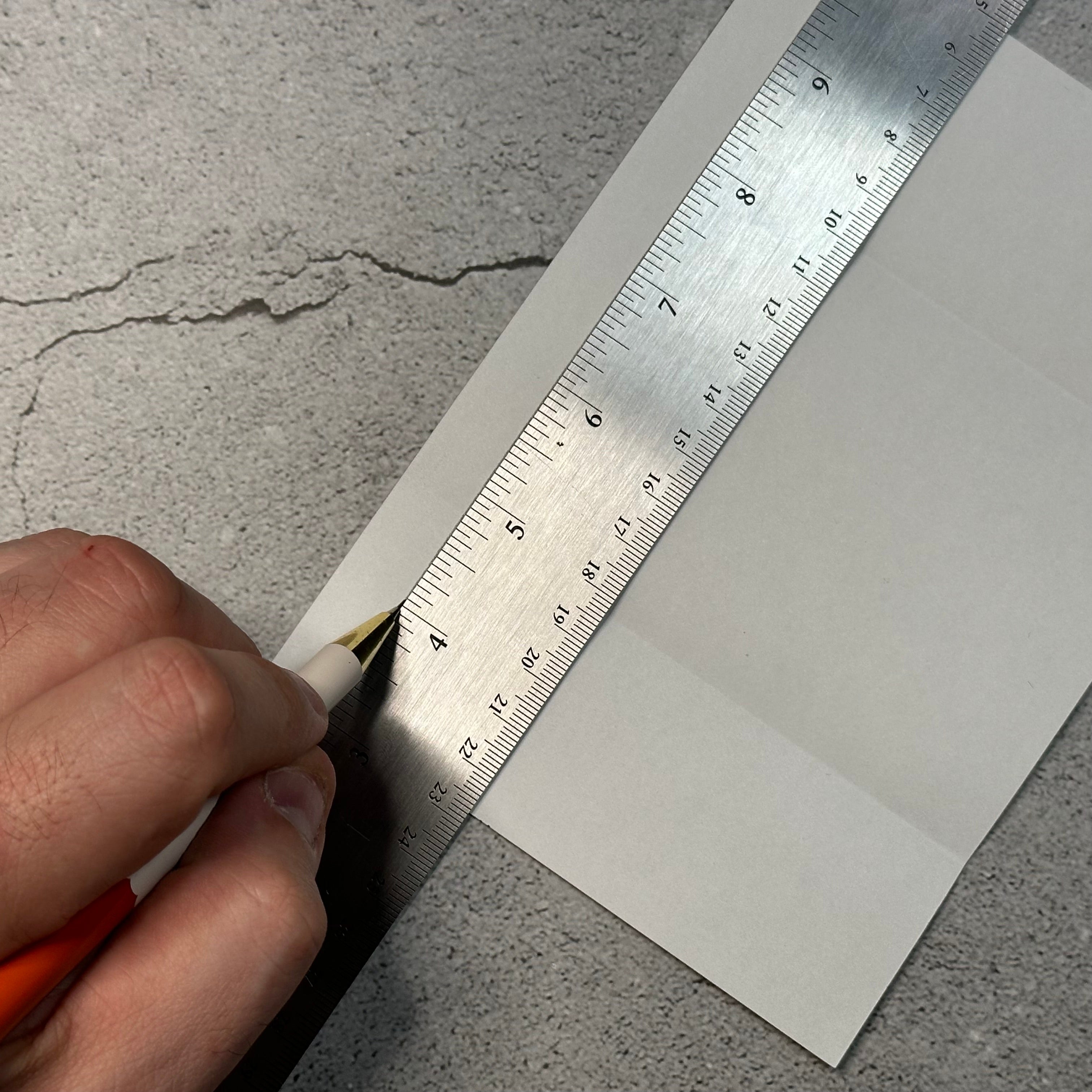 using a pencil to draw a line down the paper with a ruler