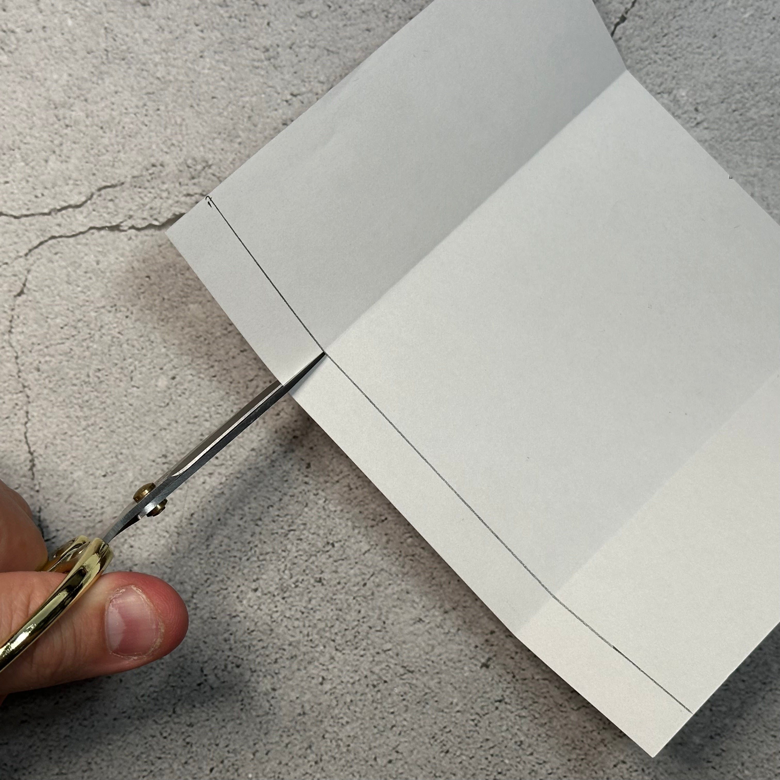 using scissors to cut the fold and line of paper.
