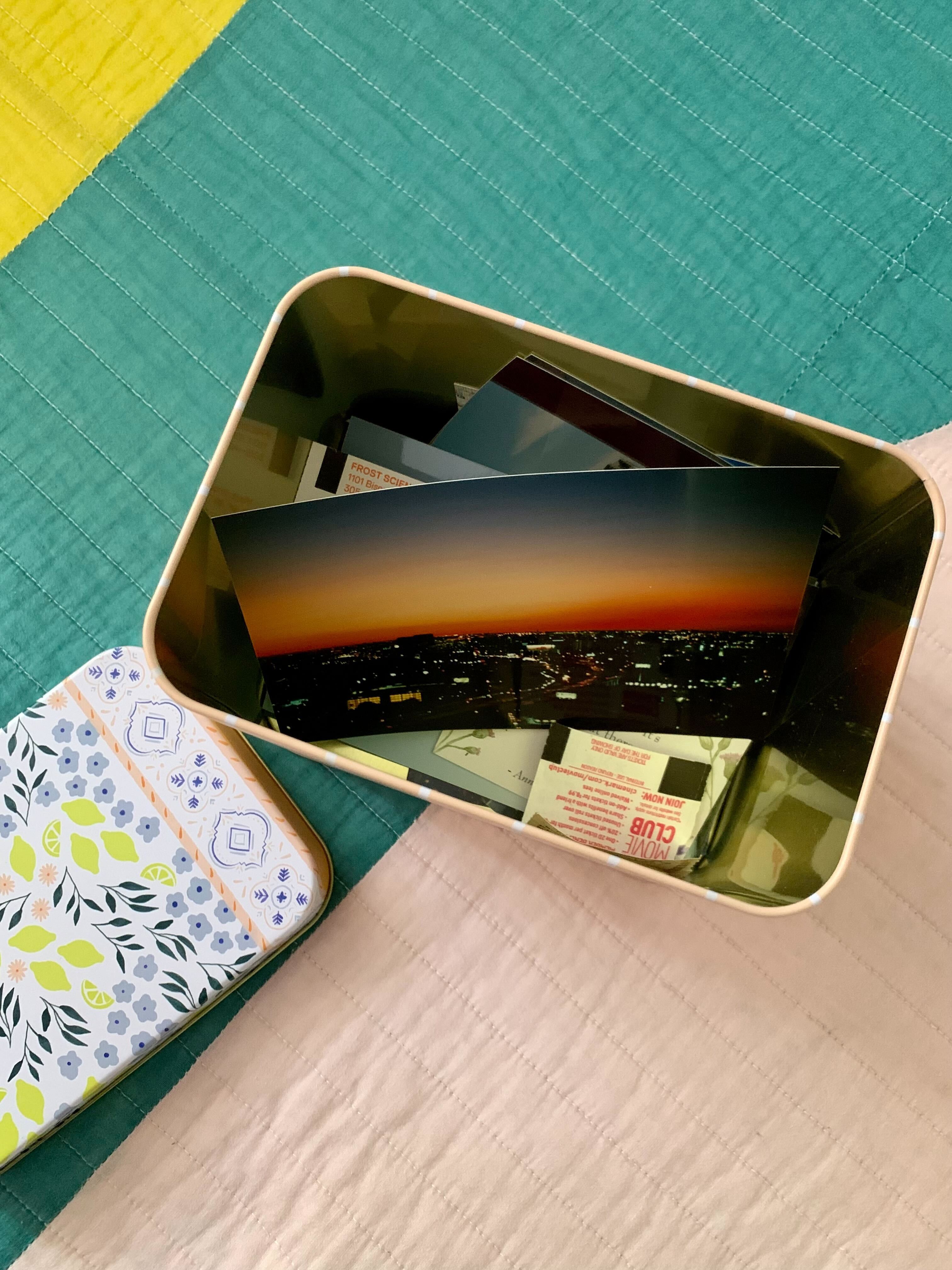 open decorative tin filled with memorable pictures, movie tickets, and trinkets