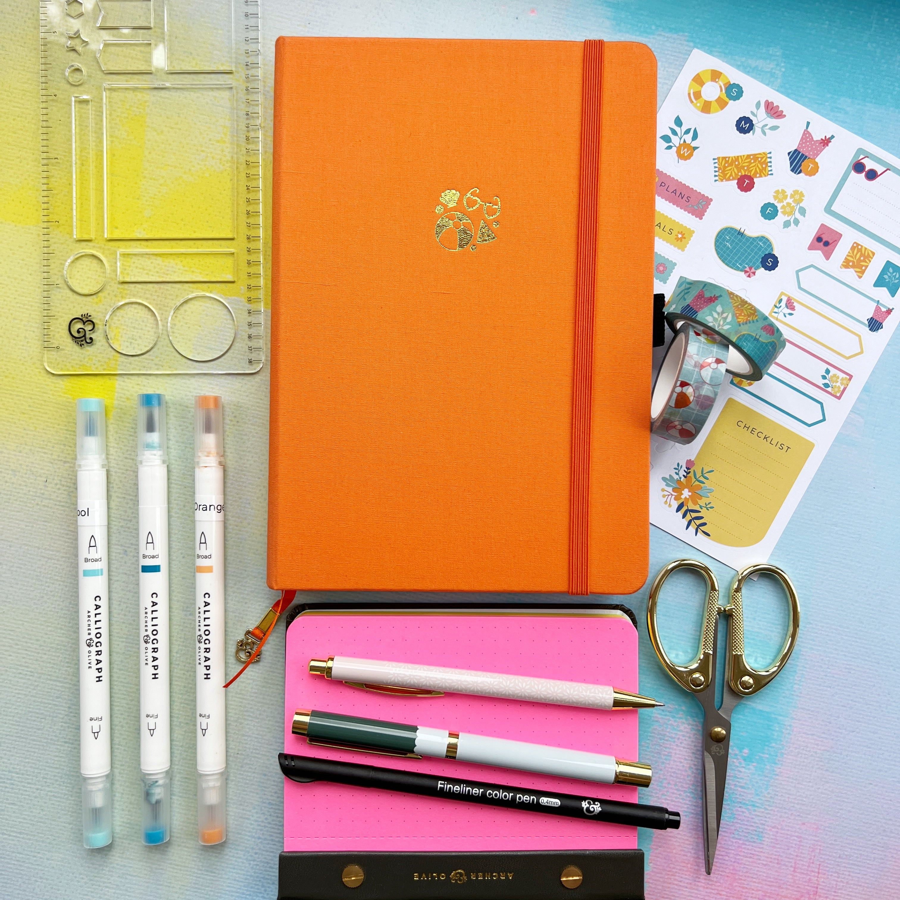 Orange journal with pens, rulers, stickers and scissors