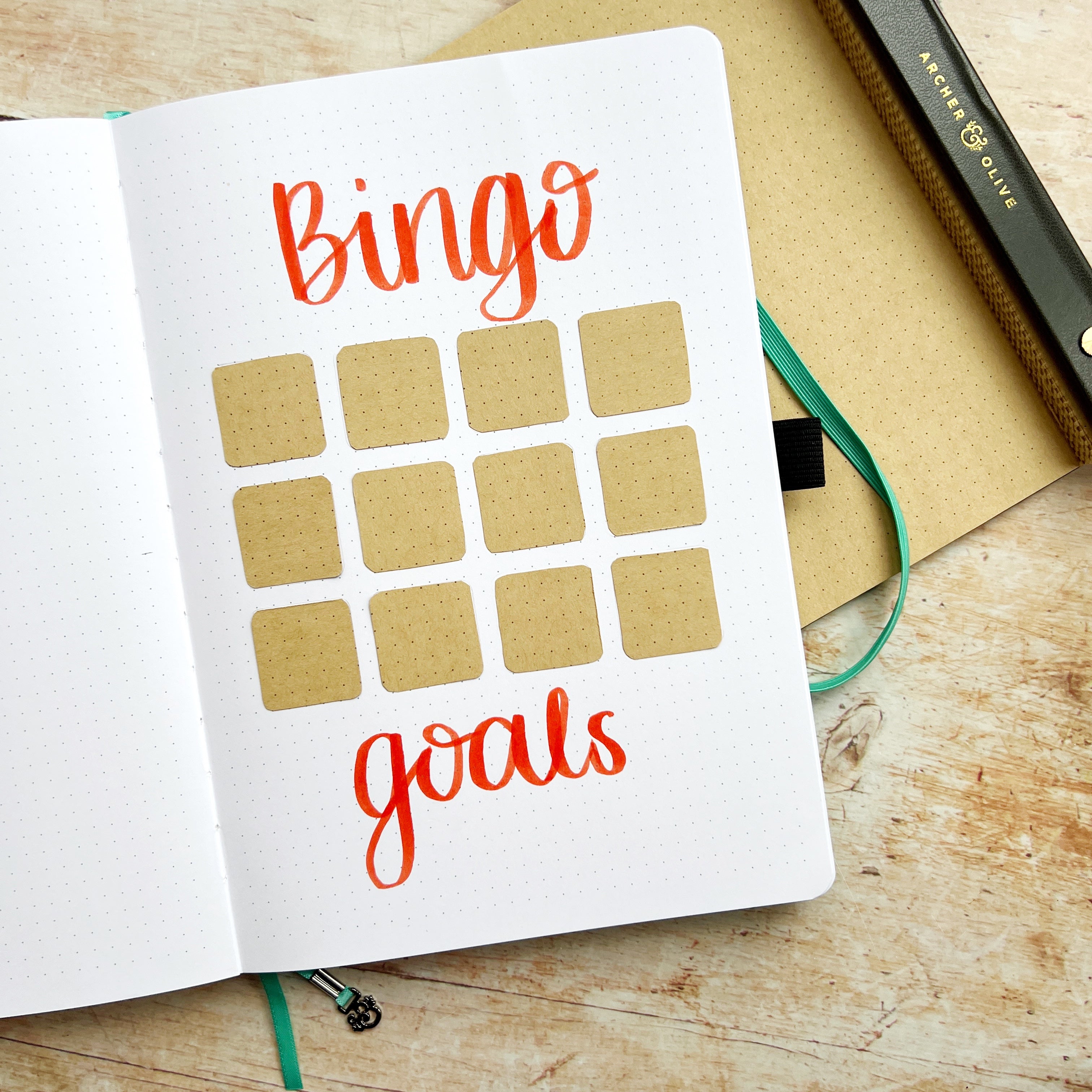 open journal, Kraft squares in place with title Bingo Goals