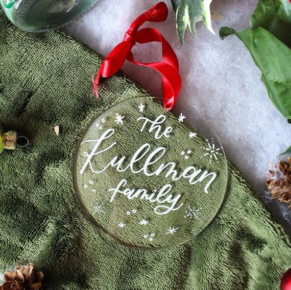 A custom acrylic Christmas family ornament is displayed with some holiday decorations.