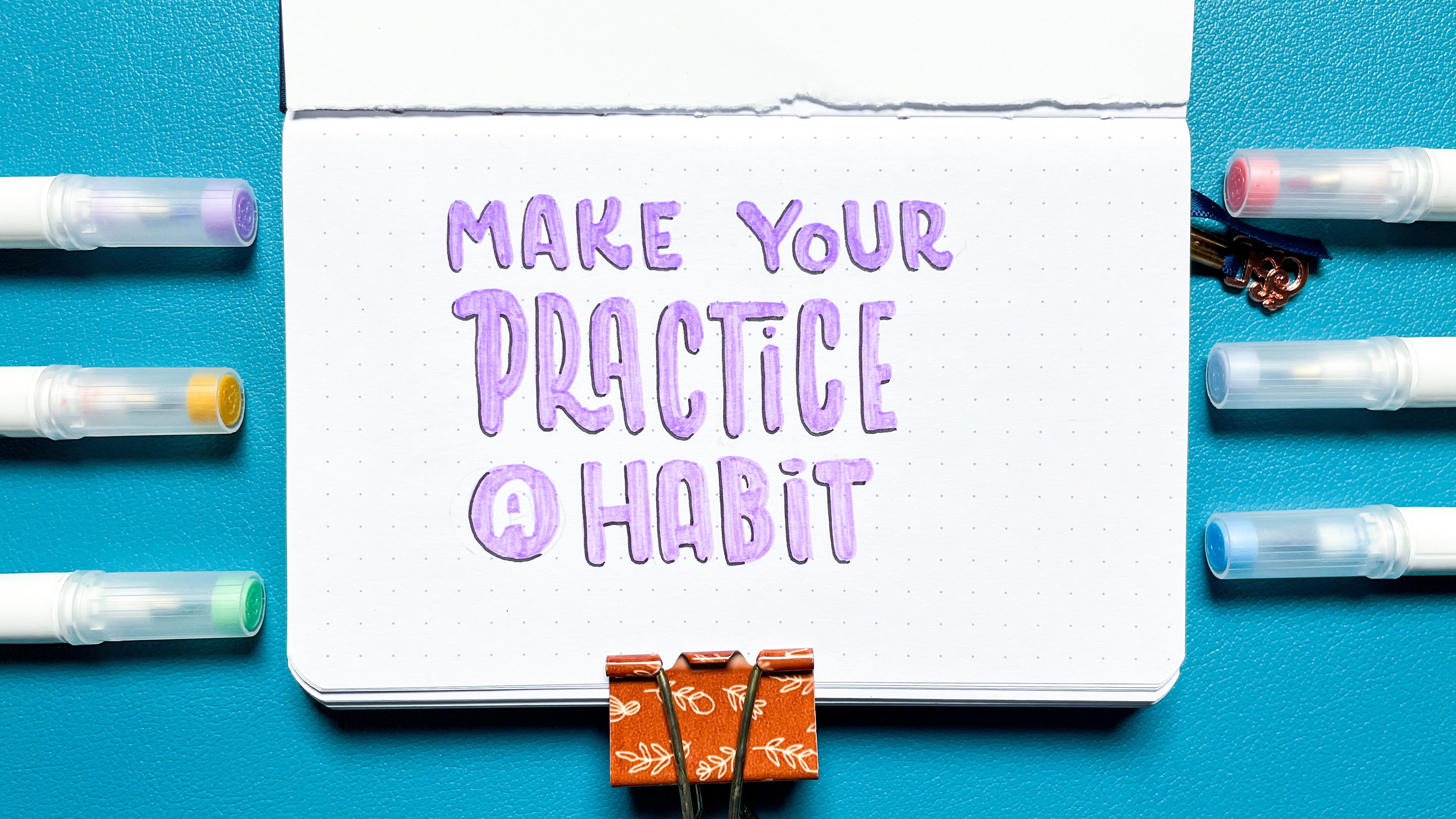 image of hand lettered "make your practice a habit" in a dot grid journal surrounded by A&O Calliographs