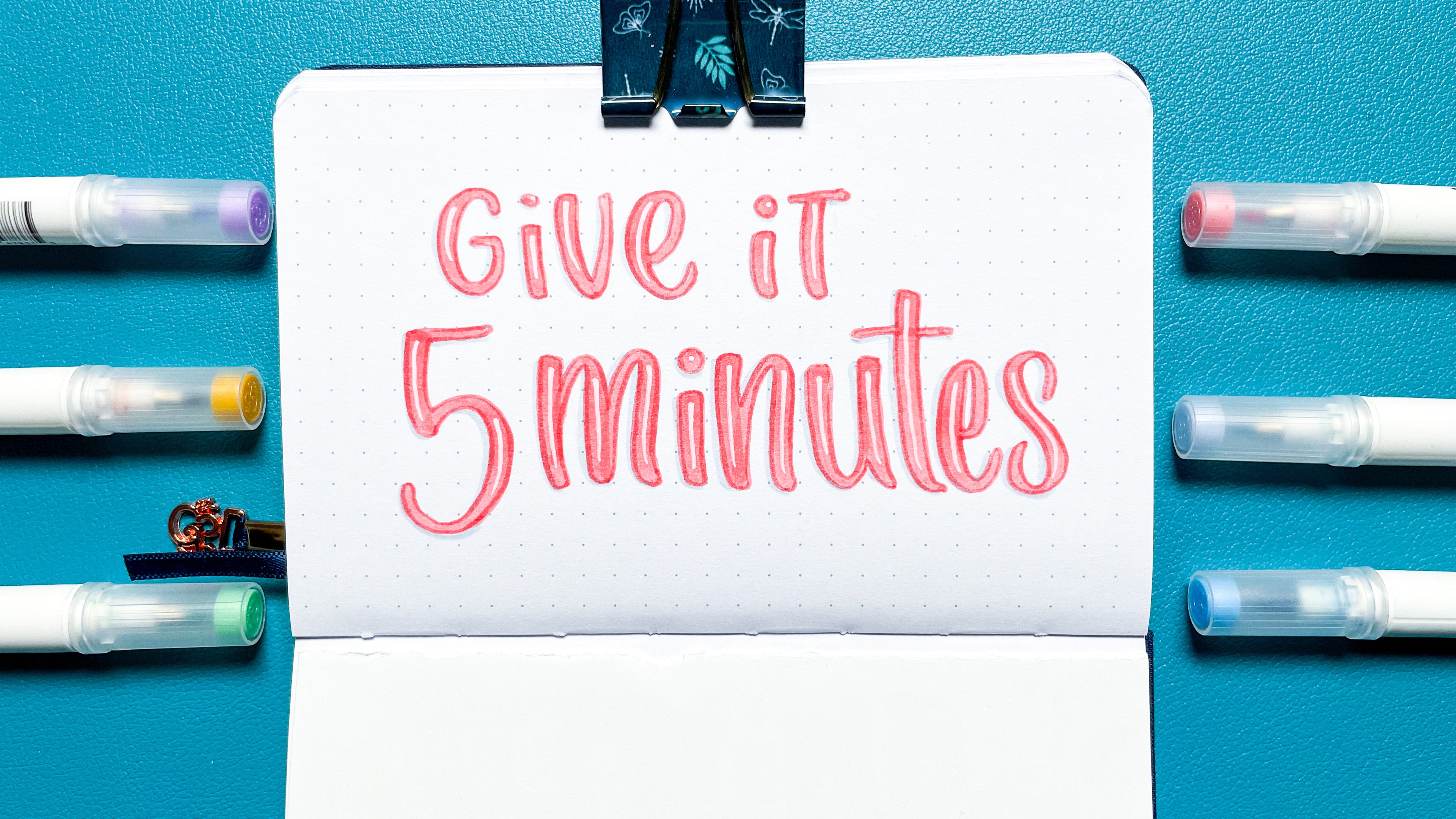 image of hand lettered "give it 5 minutes" in a dot grid journal surrounded by A&O Calliographs