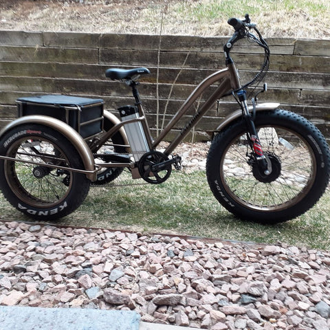 An electric Fat Trike is near a stone wall in a park