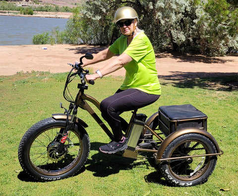 A woman is wearing a helmet while sitting on her electric Fat trike.