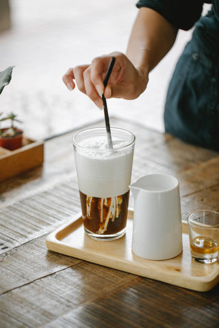 A woman stirring cold brew and cold foam. 