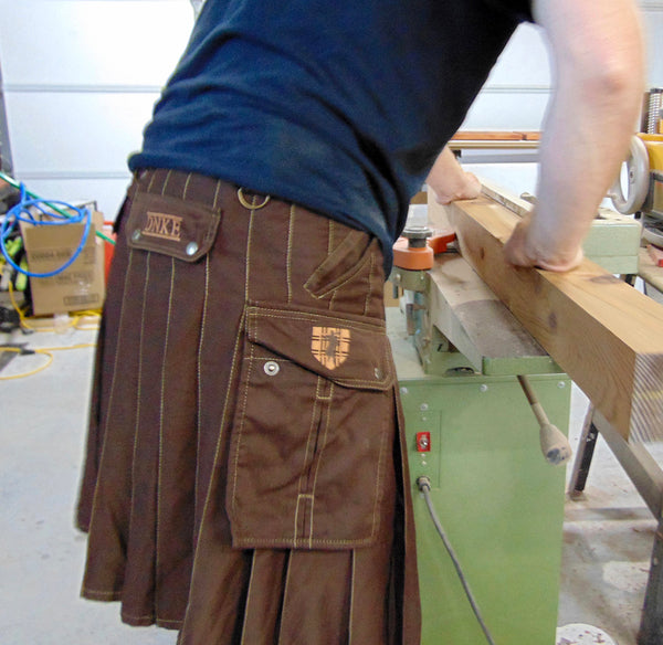 a man wearing a utility kilt operates a table saw