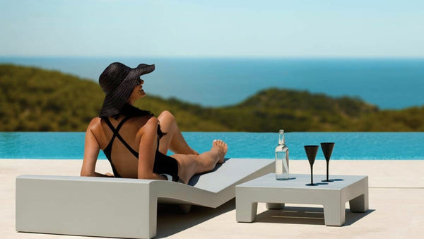Woman drinking wine poolside using the Jut Sun Chaise Table