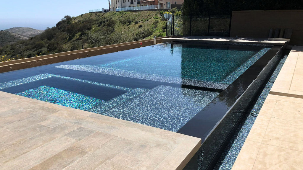 An all glass tile pool with black glass tile overlooking a stunning, forested mountain side.