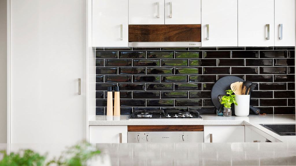 black backsplash tile in a kitchen with white cabinets and countertops