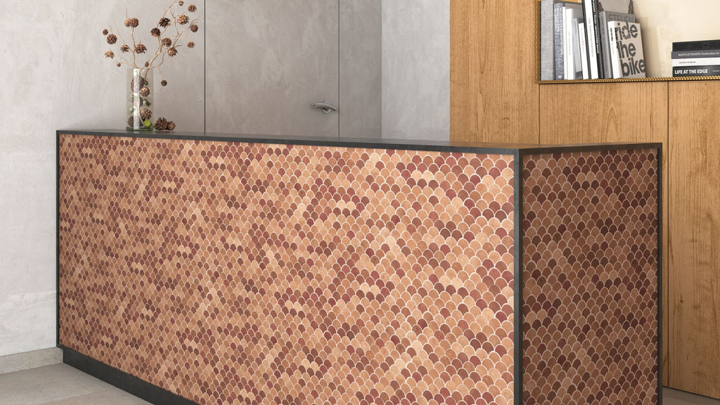 Matte, glass tile in a brick red and orange color. It's in a fish scale shape and covers the entire surface of a reception desk.