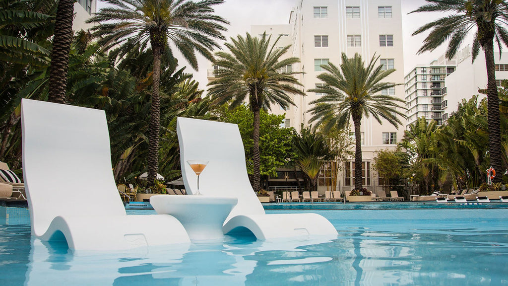 Two Signature Lowback chairs set up in a resort pool. There's a side table between them with a tropical looking drink.
